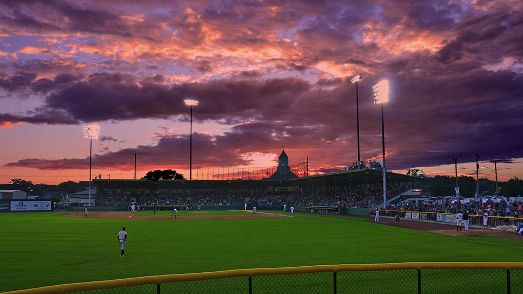 Baseball game beneath a colorful sunset in Clinton
